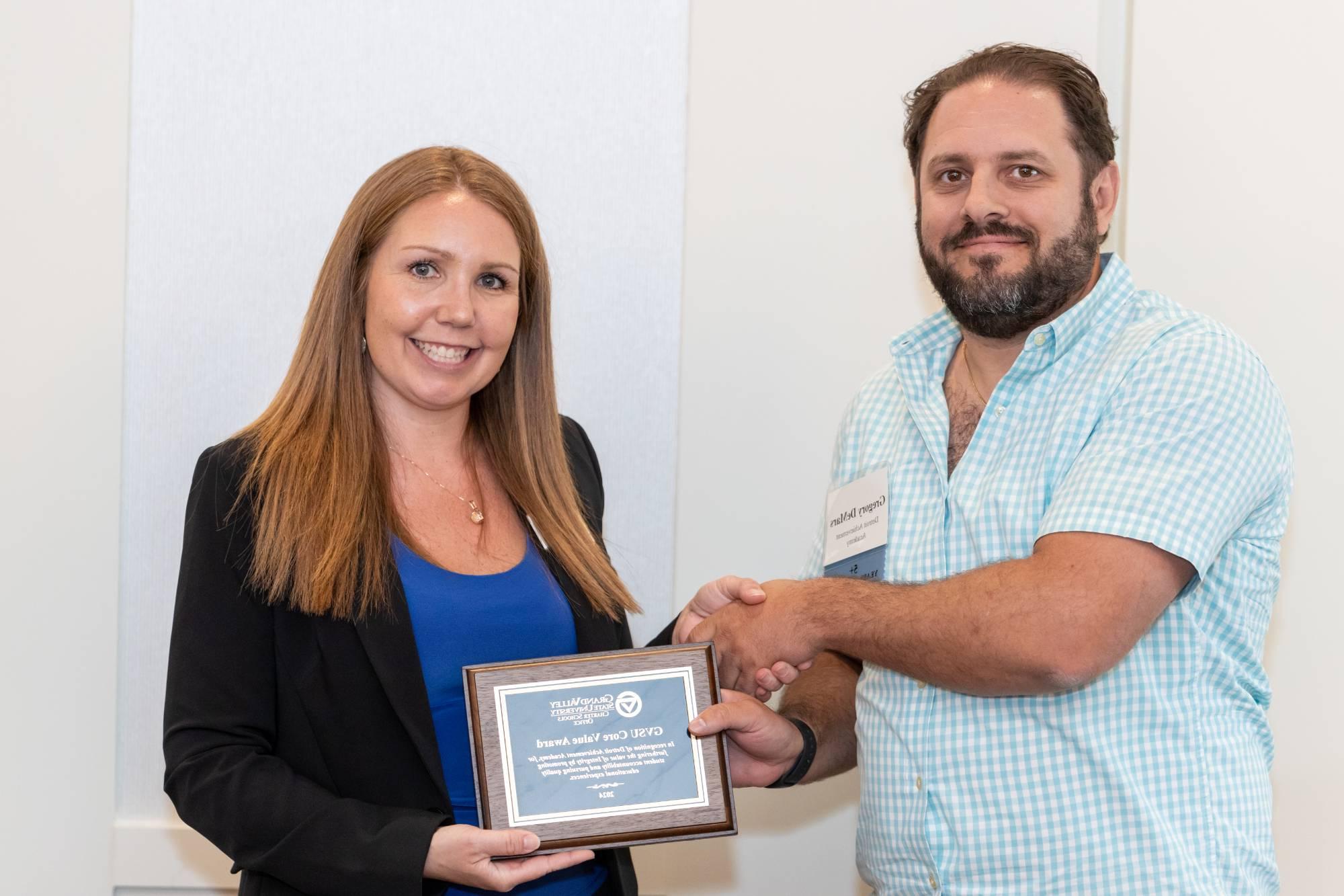 A board member from Detroit Achievement Academy accepting the award from Gretchen Lahaie